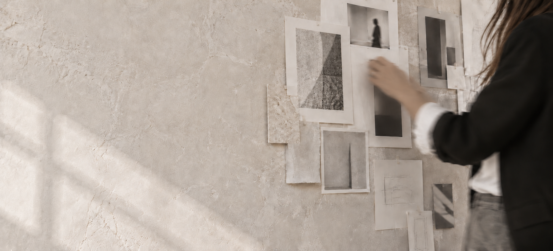 Detalle del proceso creativo: mano en movimiento ante un panel de ideas en tonos piedra